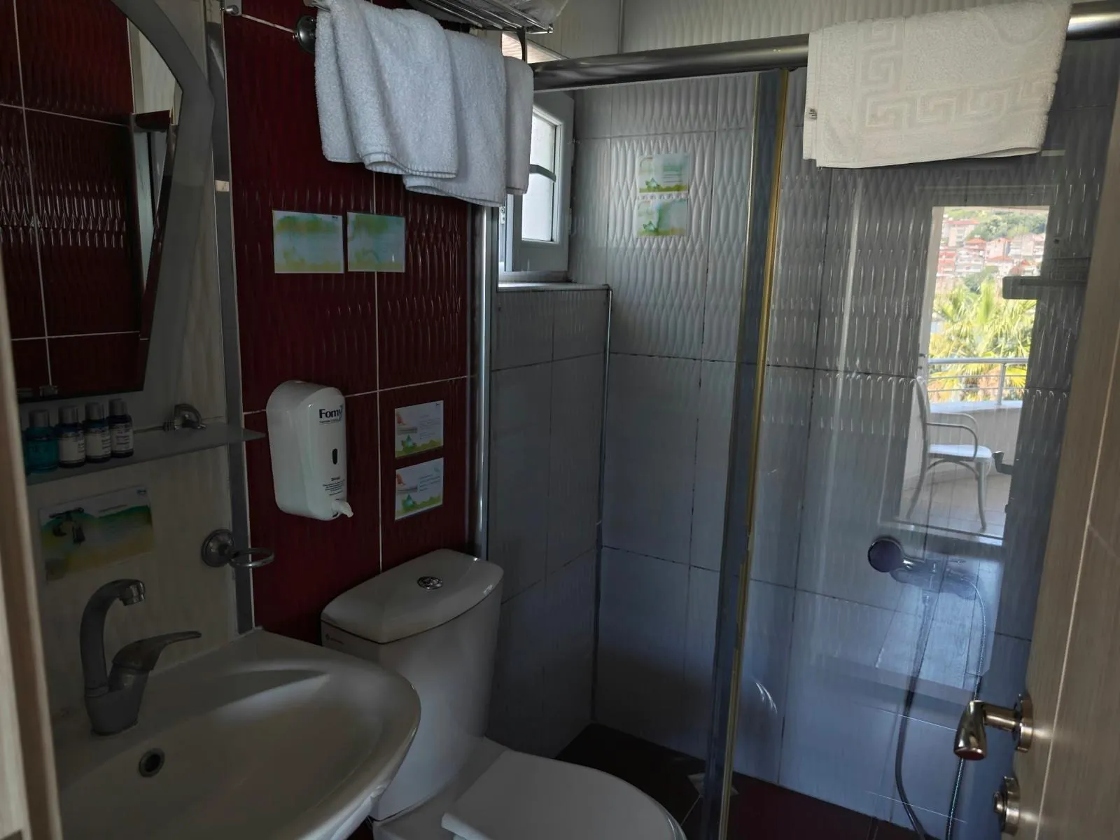 Aile odası banyosu: duş, lavabo, havlular ve bordo duvar paneli